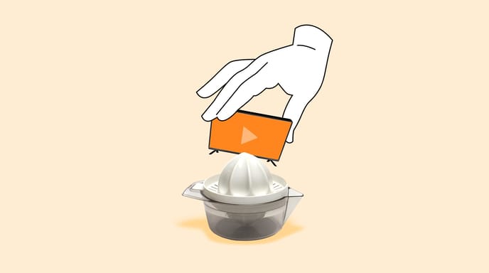 A hand holds a tv displaying an orange screen and play button over a citrus hand juicer