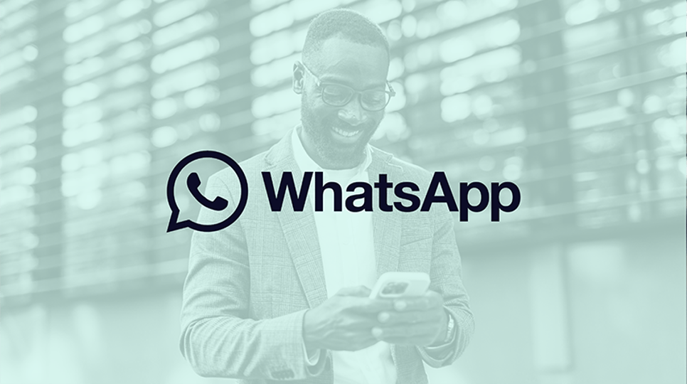 Das Bild zeigt einen Mann, der lächelt und auf sein Smartphone schaut. Das WhatsApp-Logo befindet sich in der Mitte